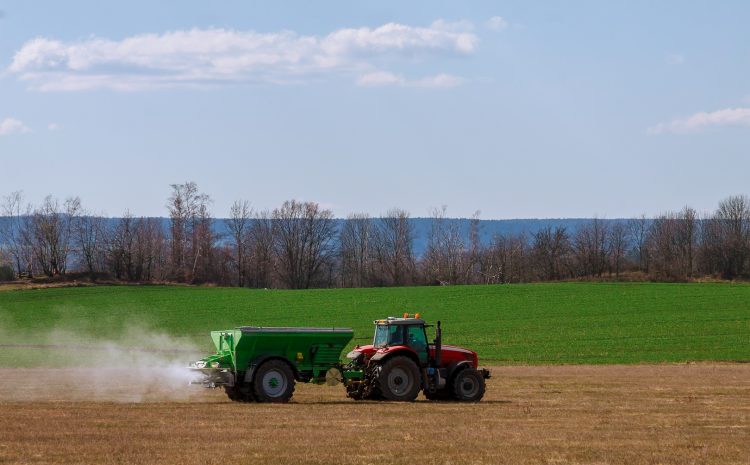 tractor spreading fertilizer on grass field agricultural work Copiar